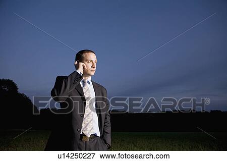 Business man using mobile phone in field View Large Photo Image Stock Photo - Business man using mobile phone in field. Fotosearch