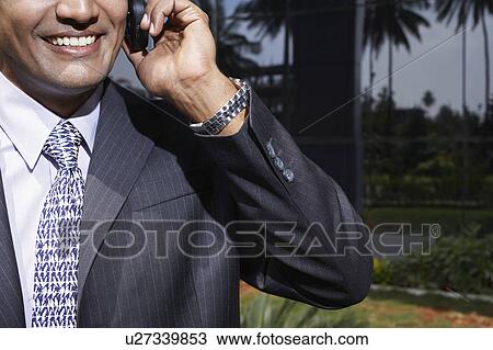 Stock Image - Business man using mobile phone outdoors. Fotosearch