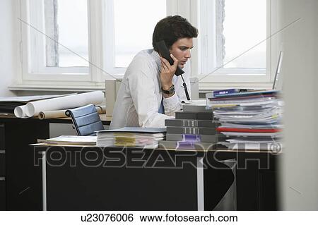 Business man using telephone at desk in office View Large Photo Image Stock Photograph - Business man using telephone at desk in office. Fotosearch