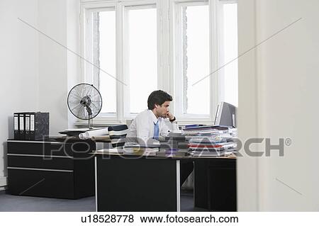Business man working at desk in office View Large Photo Image Stock Photo - Business man working at desk in office. Fotosearch