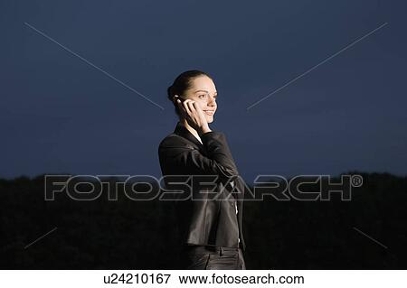 Stock Photo - Business woman using mobile phone in field. Fotosearch