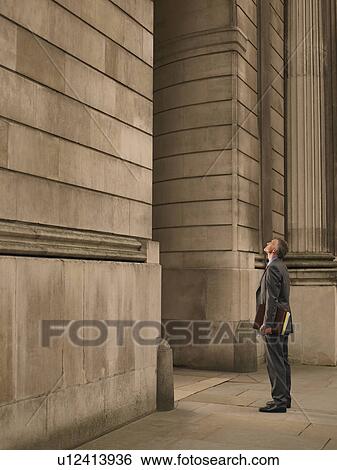 Stock Photograph - Businessman facing monumental building. Fotosearch