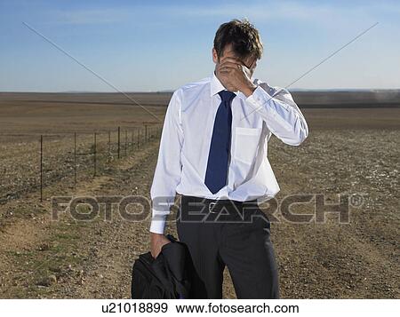 Stock Photo - Businessman holding his head in the middle of nowhere. Fotosearch