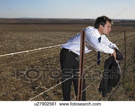 Businessman leaning on fence in the middle of nowhere View Large Photo Image Stock Image - Businessman leaning on fence in the middle of nowhere. Fotosearch