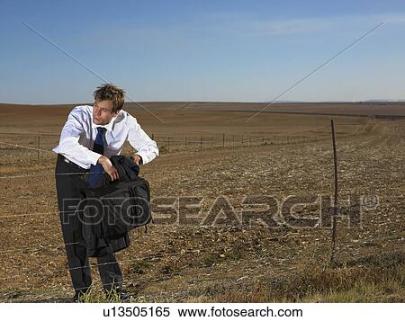 Businessman leaning on fence in the middle of nowhere View Large Photo Image Stock Photography - Businessman leaning on fence in the middle of nowhere. Fotosearch