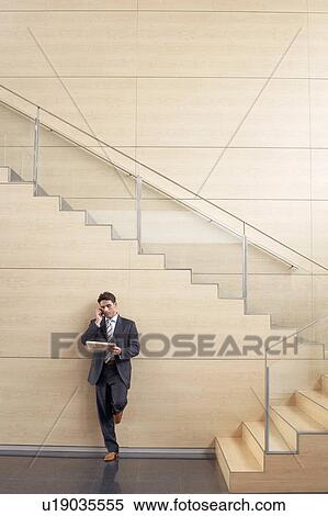 Businessman on cell phone at bottom of stairway View Large Photo Image Stock Photography - Businessman on cell phone at bottom of stairway. Fotosearch