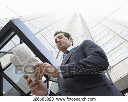 Businessman reading newspaper outside office building, (low angle view) View Large Photo Image Stock Image - Businessman reading newspaper outside office building, (low angle view). Fotosearch