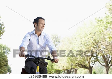 Businessman riding bicycle in park, low angle View Large Photo Image Stock Photo - Businessman riding bicycle in park, low angle. Fotosearch
