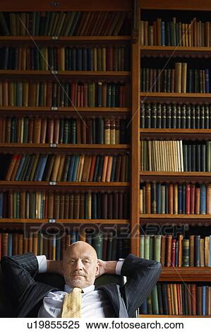 Businessman Sitting in Library, hands behind head View Large Photo Image Stock Photography - Businessman Sitting in Library, hands behind head. Fotosearch