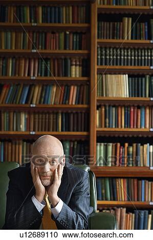 Businessman Sitting in Library, head in hands View Large Photo Image Stock Image - Businessman Sitting in Library, head in hands. Fotosearch