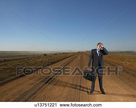 Businessman standing in road holding his head View Large Photo Image Stock Image - Businessman standing in road holding his head. Fotosearch