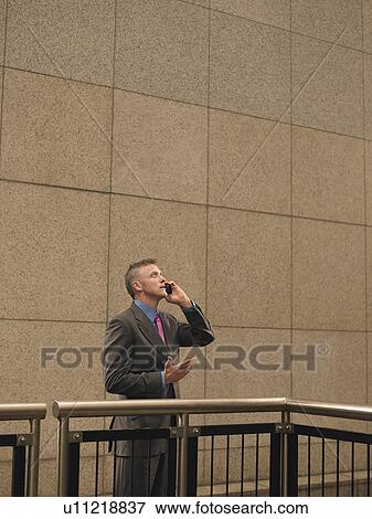 Businessman talking on mobile phone, looking up View Large Photo Image Stock Photo - Businessman talking on mobile phone, looking up. Fotosearch
