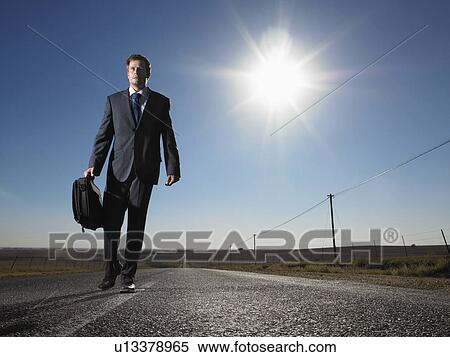 Businessman walking down road in isolated landscape View Large Photo Image Stock Photography - Businessman walking down road in isolated landscape. Fotosearch
