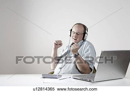 Stock Photography - Businessman with earphones relaxing at desk. Fotosearch