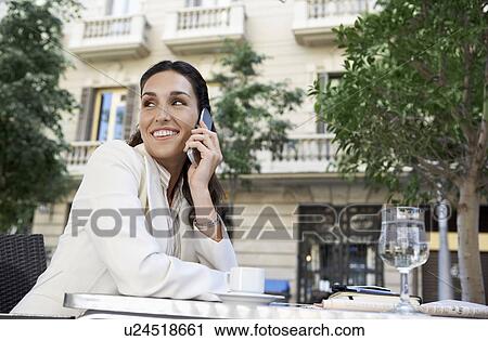 Stock Image - Businesswoman using mobile phone at outdoor cafe. Fotosearch