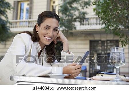 Stock Photography - Businesswoman using mobile phone at outdoor cafe. Fotosearch
