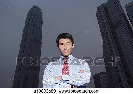 China, Hong Kong, business man standing in front of International Finance Centre building, low angle view, portrait View Large Photo Image Stock Photo - China, Hong Kong, business man standing in front of International Finance Centre building, low angle view, portrait. Fotosearch