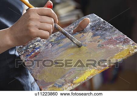 Stock Image - Close-up of woman's hands with brush and palette. Fotosearch