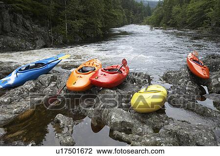 Stock Image - Colourful kayaks by river. Fotosearch