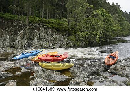Stock Photo - Colourful kayaks by river. Fotosearch