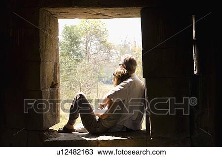 Stock Image - Couple Cuddling in Window of Stone Building. Fotosearch