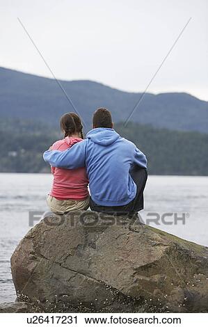 Couple embracing on rock by ocean View Large Photo Image Stock Image - Couple embracing on rock by ocean. Fotosearch