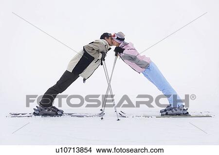 Couple leaning towards each other standing on skis, side view View Large Photo Image Picture - Couple leaning towards each other standing on skis, side view. Fotosearch
