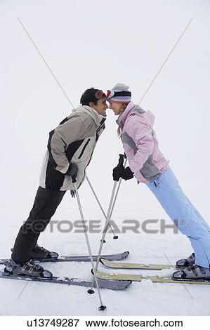 Couple leaning towards each other standing on skis, side view View Large Photo Image Stock Photo - Couple leaning towards each other standing on skis, side view. Fotosearch