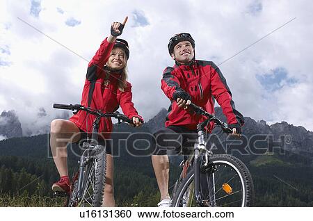 Couple on bikes in countryside, woman pointing View Large Photo Image Stock Image - Couple on bikes in countryside, woman pointing. Fotosearch