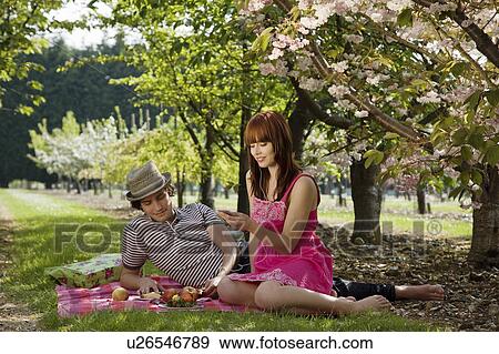 Stock Photo - Couple Picnicking in Orchard. Fotosearch