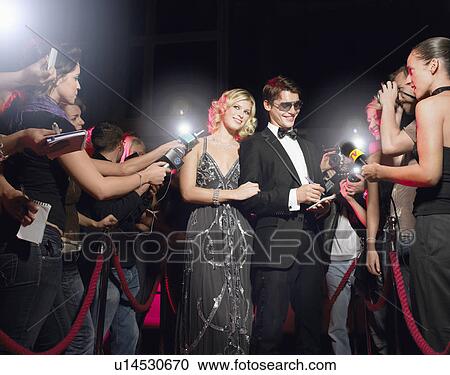 Stock Image - Couple signing autographs on red carpet. Fotosearch