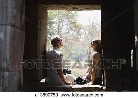 Stock Image - Couple Sitting in Window of Stone Building. Fotosearch