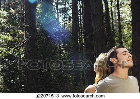 Couple standing back to back in woodlands enjoying sunbeam View Large Photo Image Stock Image - Couple standing back to back in woodlands enjoying sunbeam. Fotosearch