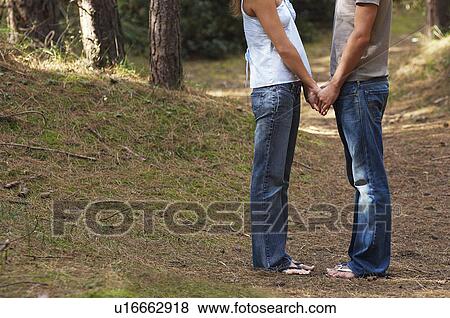 Couple standing in Forest Holding Hands, low section, side view View Large Photo Image Stock Photo - Couple standing in Forest Holding Hands, low section, side view. Fotosearch