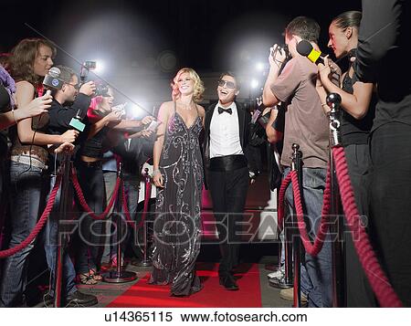 Stock Photography - Couple walking down red carpet, photographed by paparazzi. Fotosearch