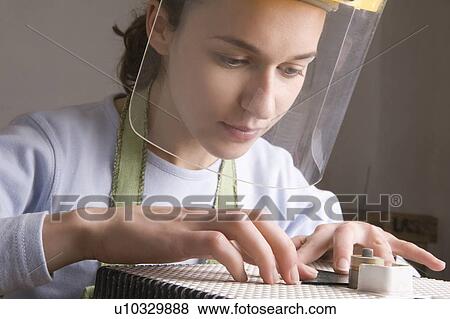 Stock Photo - Craftswoman works on bench with visor. Fotosearch
