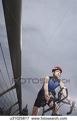 Stock Photo - Cyclist riding on foot bridge, low angle view. Fotosearch