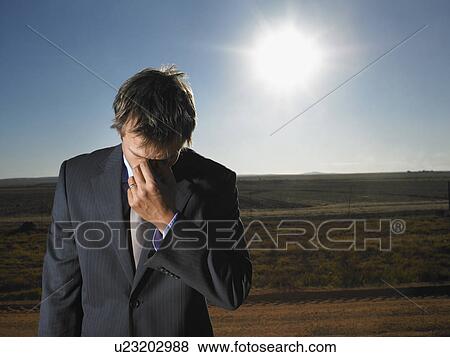 Stock Photo - Despairing businessman in barren landscape. Fotosearch