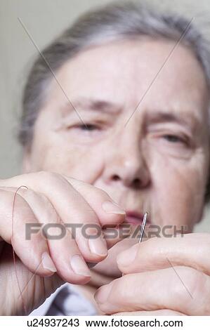 Elderly lady threads a needle View Large Photo Image Stock Image - Elderly lady threads a needle. Fotosearch