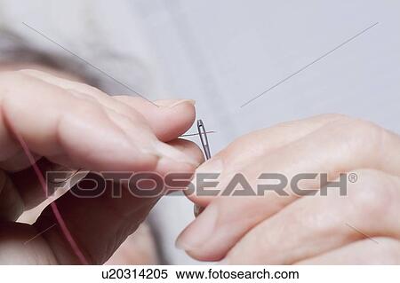 Stock Photography - Elderly lady threads a needle. Fotosearch