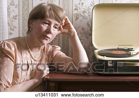 Elderly woman sits listening to old fashioned record player View Large Photo Image Stock Image - Elderly woman sits listening to old fashioned record player. Fotosearch