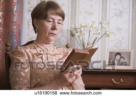 Elderly woman sits reading book in Russian apartment View Large Photo Image Stock Photo - Elderly woman sits reading book in Russian apartment. Fotosearch