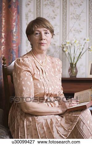 Stock Photo - Elderly woman sits with book in Russian apartment. Fotosearch