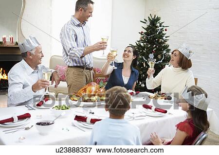 Stock Photo - Family toasting at table at christmas dinner. Fotosearch