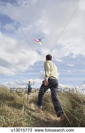 Father and daughter (5-6) flying kite on dunes View Large Photo Image Stock Image - Father and daughter (5-6) flying kite on dunes. Fotosearch