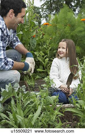 Stock Image - Father and daughter (5-6) gardening. Fotosearch