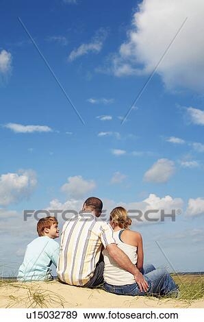 Father and mother sitting with son on sand dune, back view View Large Photo Image Stock Photo - Father and mother sitting with son on sand dune, back view. Fotosearch