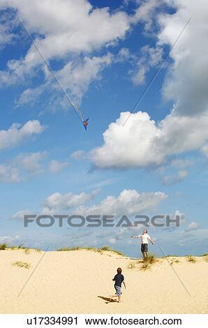 Father and Son Flying Kite on sand dune on beach View Large Photo Image Stock Image - Father and Son Flying Kite on sand dune on beach. Fotosearch