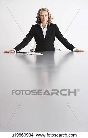 Picture - Female Business Executive Sitting by table, arms outstretched. Fotosearch