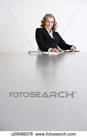 Stock Photograph - Female Business Executive Sitting by table. Fotosearch
